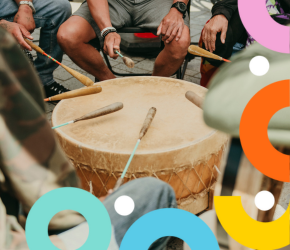 An Indigenous group sings and plays the dance drum together.