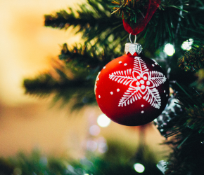 An festive ornament hanging from a spruce tree.