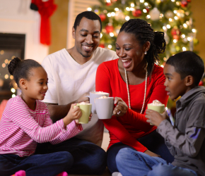 A family gathers around a holiday tree for a warm beverage.