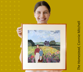 A smiling woman holding artwork by Connie Mitchell, The Homestead