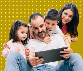 A smiling family of four exploring CBC corner on their tablet. 