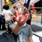 A boy holding a bubble in his soapy hand.