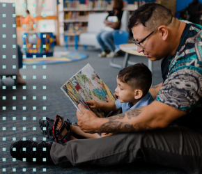 A boy and his dad reading a book.