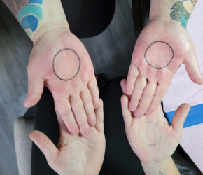Two hands with a circle tattooed on each palm.