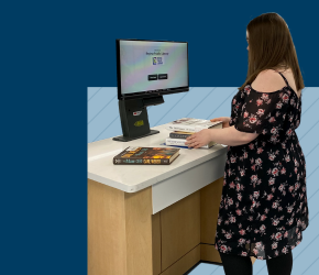 A person checking out their library books at the self-check kiosk.