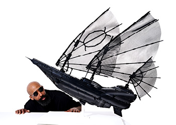 Artist Ekow Nimako is pictured with a flying ship built from black Lego bricks. 